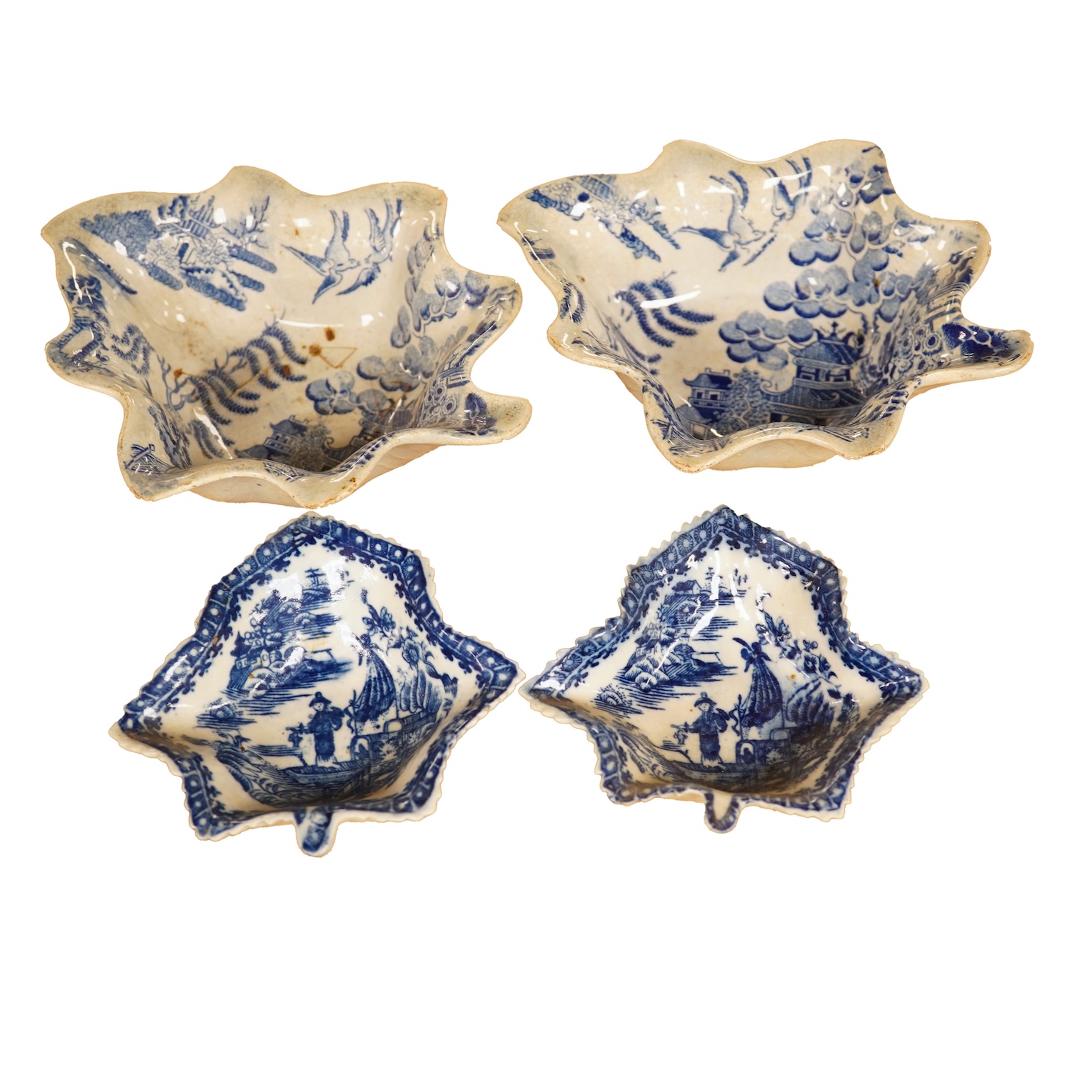 Two late 18th century Worcester or Caughley Cormorant fisherman pattern leaf pickle dishes and two early 19th century blue and white pottery leaf pickle dishes, largest 14.5cm long.